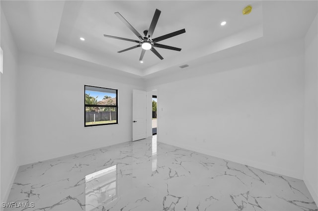 spare room with baseboards, a raised ceiling, ceiling fan, recessed lighting, and marble finish floor
