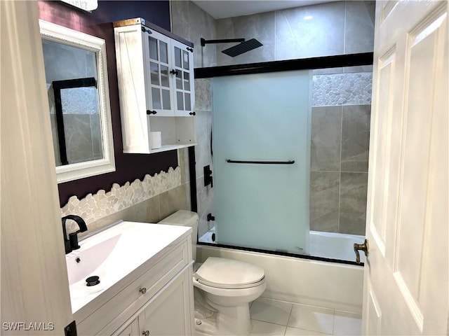 bathroom featuring toilet, tile patterned floors, vanity, and enclosed tub / shower combo