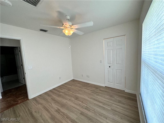 unfurnished bedroom featuring visible vents, baseboards, ceiling fan, and wood finished floors