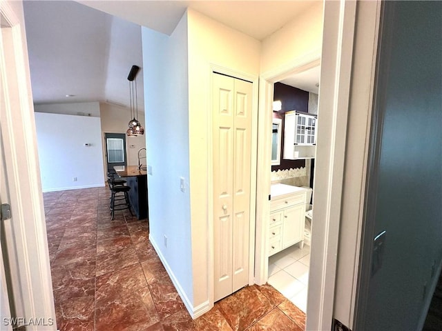 hallway featuring baseboards and lofted ceiling