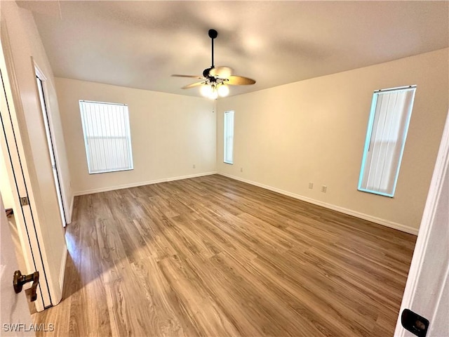 empty room with ceiling fan, wood finished floors, and baseboards