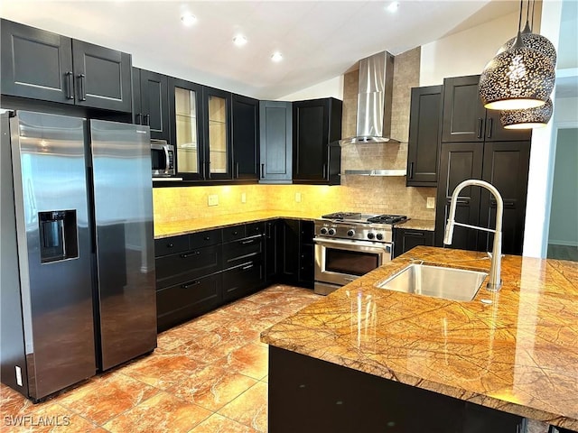 kitchen with dark cabinets, appliances with stainless steel finishes, wall chimney range hood, lofted ceiling, and a sink