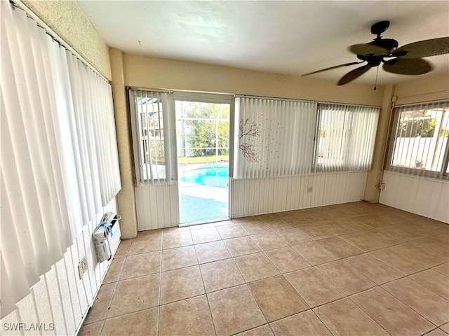 empty room featuring light tile patterned floors, a ceiling fan, and a wealth of natural light