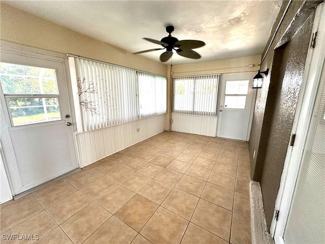 unfurnished sunroom featuring a ceiling fan