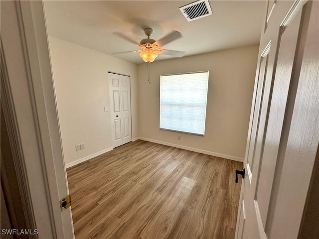 unfurnished bedroom featuring light wood-style flooring, baseboards, a ceiling fan, and visible vents