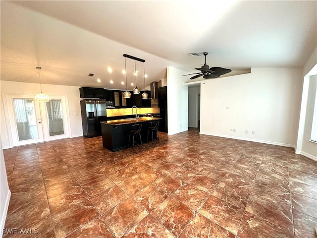 kitchen with fridge with ice dispenser, open floor plan, dark countertops, dark cabinetry, and lofted ceiling