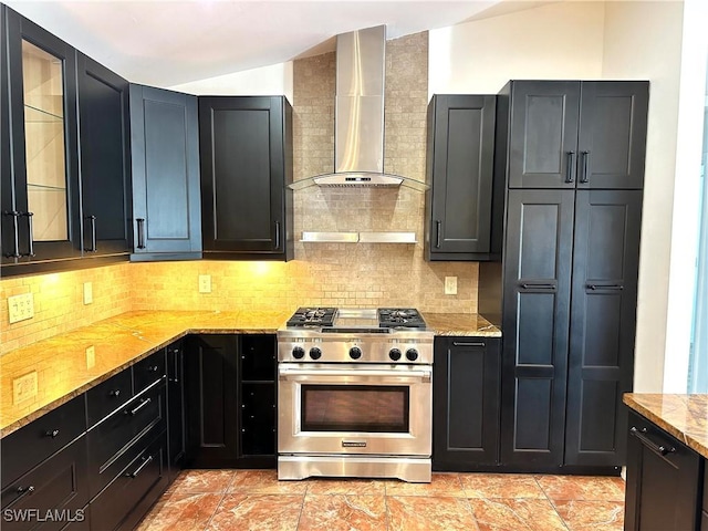 kitchen featuring wall chimney exhaust hood, light stone countertops, high end stove, tasteful backsplash, and vaulted ceiling