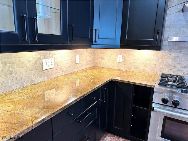 kitchen with stainless steel stove, glass insert cabinets, blue cabinets, and decorative backsplash