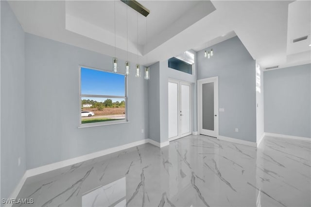 empty room with visible vents, baseboards, a raised ceiling, and marble finish floor