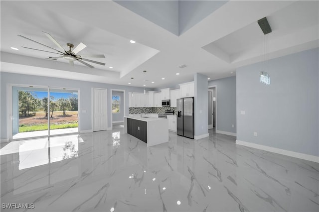 kitchen featuring a kitchen island, light countertops, stainless steel appliances, open floor plan, and baseboards