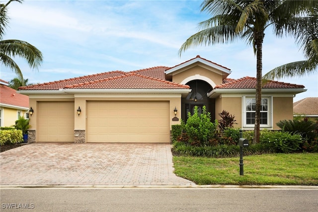 view of front of property featuring stucco siding, stone siding, a tile roof, a garage, and driveway