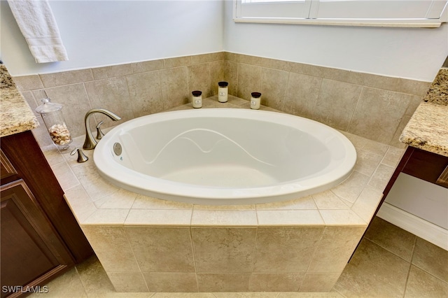bathroom with tile patterned floors, a garden tub, and vanity