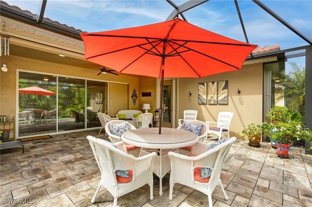 view of patio / terrace featuring outdoor dining area, a lanai, and a ceiling fan