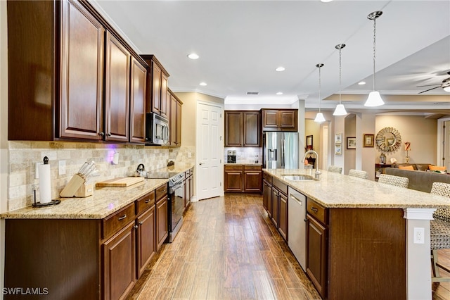 kitchen featuring a sink, open floor plan, appliances with stainless steel finishes, crown molding, and dark wood-type flooring