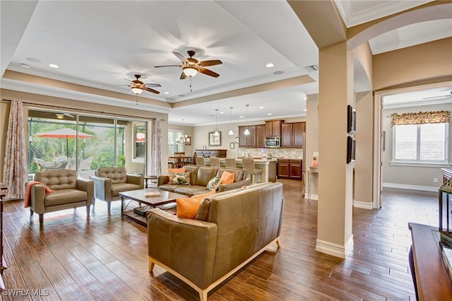 living room featuring ornamental molding, recessed lighting, dark wood-style floors, a raised ceiling, and ceiling fan