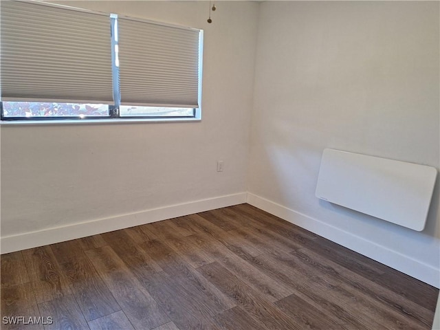 empty room featuring dark wood-type flooring and baseboards