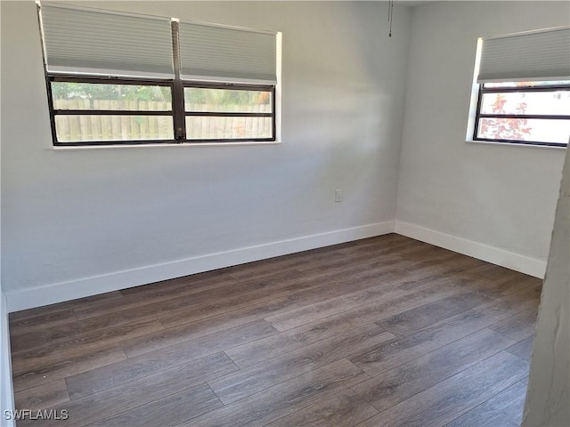 empty room with baseboards, dark wood finished floors, and a wealth of natural light