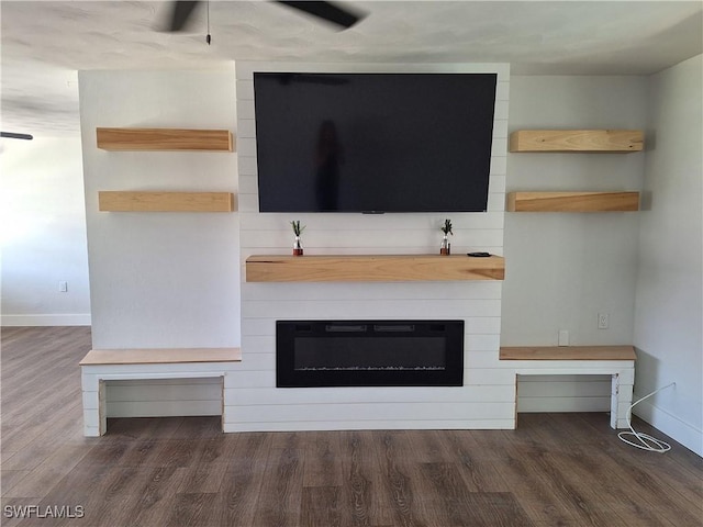 interior space featuring a large fireplace, baseboards, ceiling fan, and wood finished floors