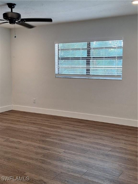 unfurnished room featuring baseboards, a ceiling fan, and dark wood-style floors