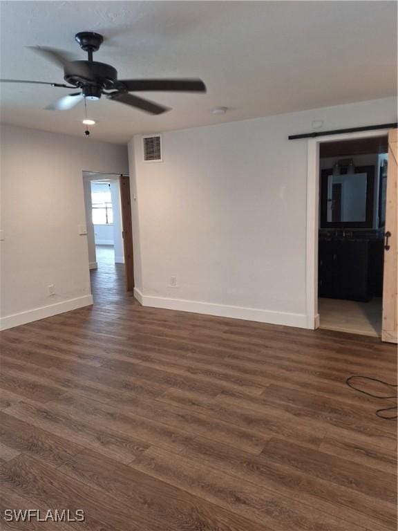 spare room with dark wood-type flooring, visible vents, baseboards, and a ceiling fan