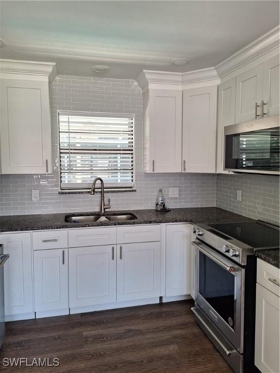 kitchen with dark stone countertops, a sink, white cabinets, and stainless steel appliances