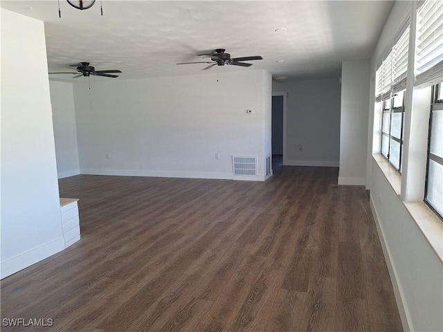 spare room featuring dark wood finished floors, visible vents, baseboards, and ceiling fan