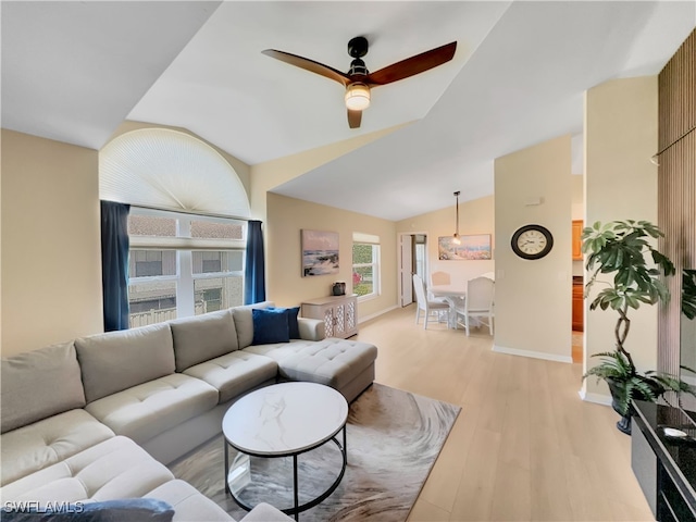 living area with lofted ceiling, light wood-type flooring, baseboards, and ceiling fan
