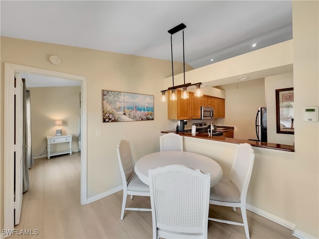 dining area featuring baseboards, light wood finished floors, and recessed lighting