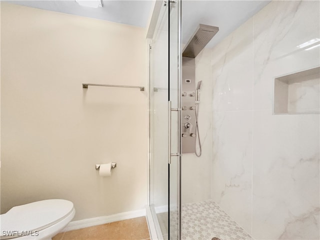 bathroom with toilet, a shower stall, tile patterned flooring, and baseboards