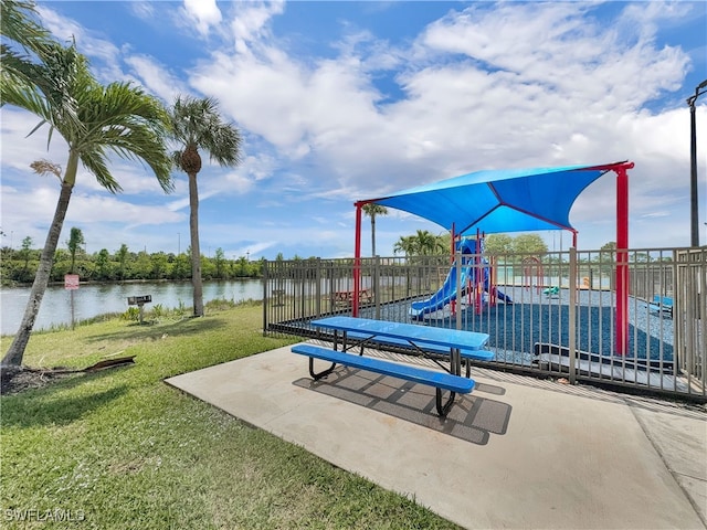 community jungle gym featuring a water view, a yard, and fence