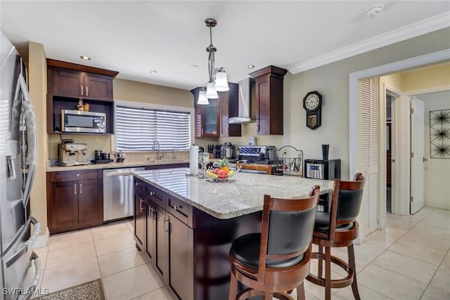 2420 6th Ave SE, Naples, FL 34117 - kitchen with wall chimney range hood, light tile patterned floors, a kitchen island, decorative light fixtures, and appliances with stainless steel finishes