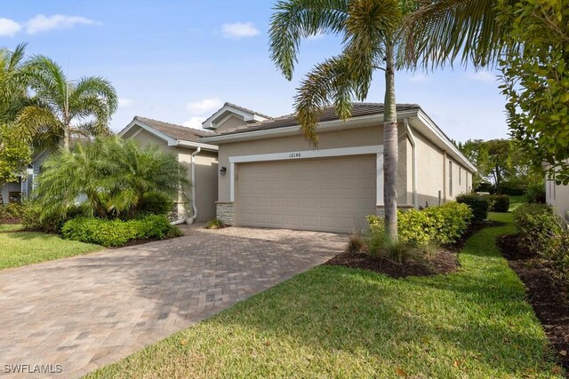 16148 Bonita Landing Cir, Bonita Springs, FL 34135 - view of front of house featuring stucco siding, decorative driveway, an attached garage, a front lawn, and a tiled roof