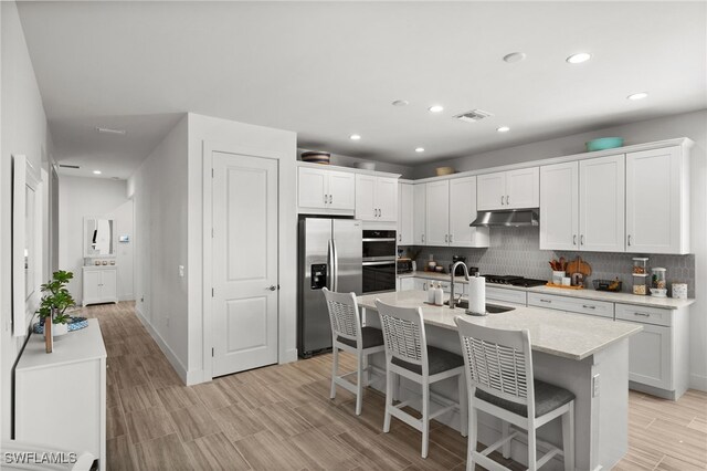 44372 Panther Dr, Punta Gorda, FL 33982 - kitchen with appliances with stainless steel finishes, under cabinet range hood, visible vents, decorative backsplash, and a sink