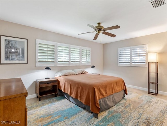 bedroom featuring visible vents, baseboards, multiple windows, and ceiling fan