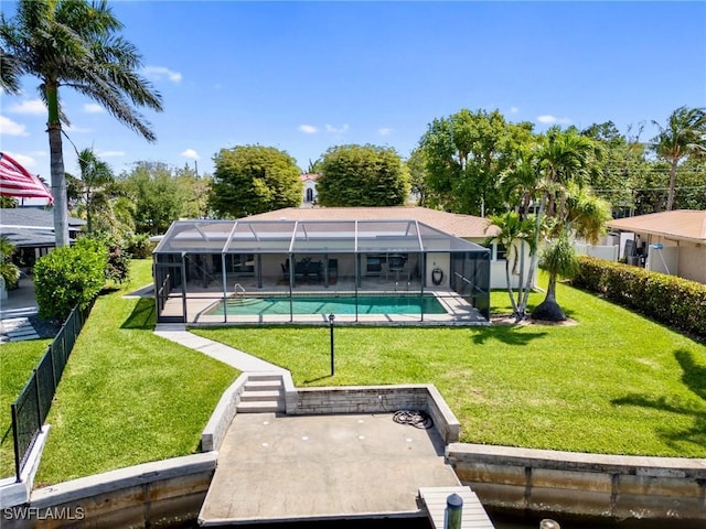 rear view of property with a yard, an outdoor pool, fence, and a lanai