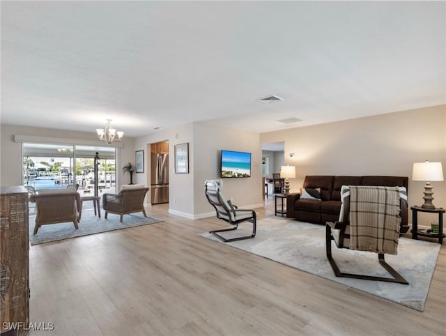 living room with baseboards, visible vents, light wood-type flooring, and an inviting chandelier