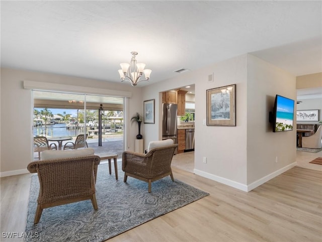 living room with light wood-style flooring, visible vents, baseboards, and a chandelier