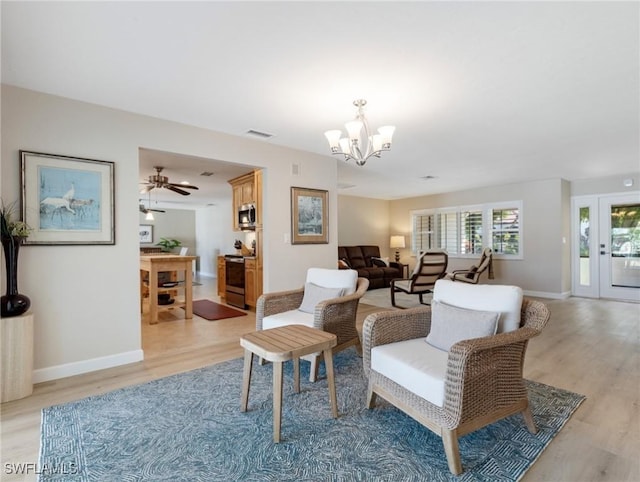 living room featuring visible vents, baseboards, light wood-type flooring, and an inviting chandelier
