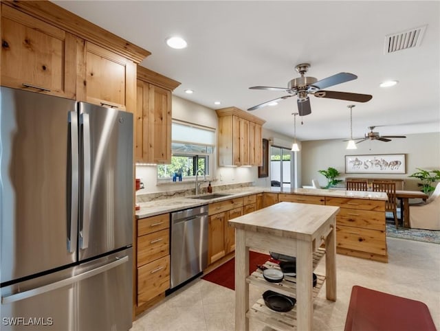 kitchen featuring visible vents, a sink, ceiling fan, appliances with stainless steel finishes, and a peninsula