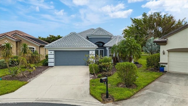 view of front of home featuring a tile roof, an attached garage, stucco siding, and concrete driveway