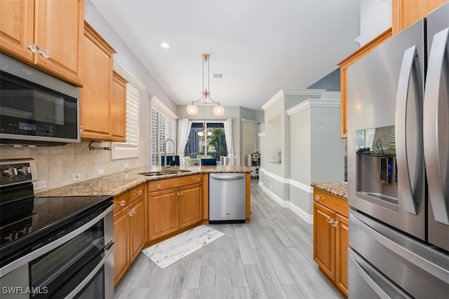 kitchen featuring light wood-style flooring, a peninsula, appliances with stainless steel finishes, light stone counters, and baseboards