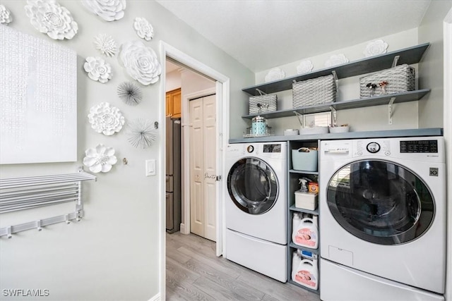 clothes washing area with light wood-style flooring, washer and clothes dryer, laundry area, and baseboards