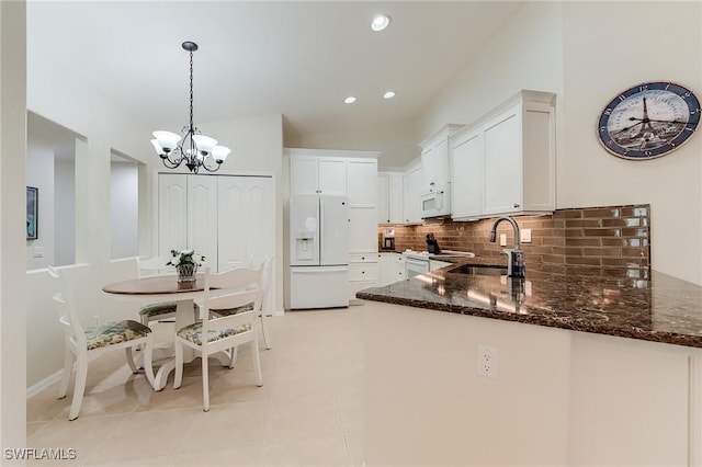 9241 Spring Run Blvd Unit 2202, Estero, FL 34135 - kitchen featuring dark stone counters, white appliances, white cabinets, a sink, and backsplash