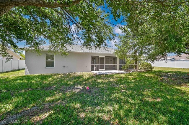 3831 Pelican Blvd, Cape Coral, FL 33914 - back of property featuring stucco siding, a fenced backyard, a sunroom, and a lawn
