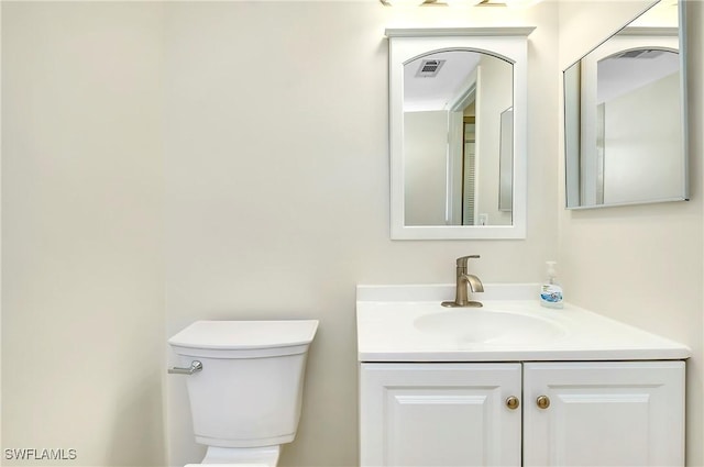 bathroom with toilet, visible vents, and vanity