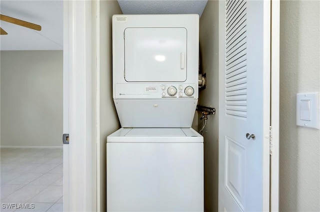 laundry area with laundry area, stacked washer and dryer, baseboards, ceiling fan, and tile patterned floors