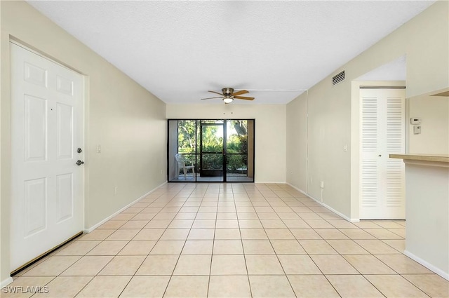 empty room featuring light tile patterned flooring, ceiling fan, visible vents, and baseboards