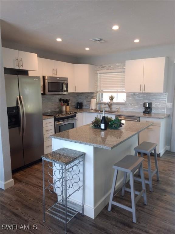 787 106th Ave N, Naples, FL 34108 - kitchen featuring appliances with stainless steel finishes, a breakfast bar, a center island, backsplash, and dark wood-type flooring