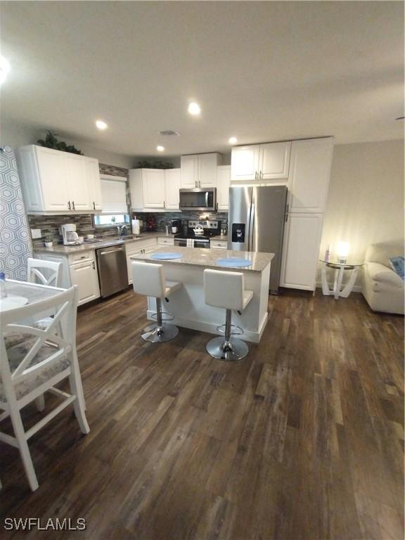 787 106th Ave N, Naples, FL 34108 - kitchen with stainless steel appliances, white cabinets, decorative backsplash, dark wood-style flooring, and recessed lighting