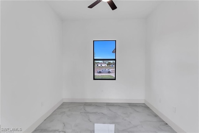 unfurnished room featuring marble finish floor, baseboards, and a ceiling fan
